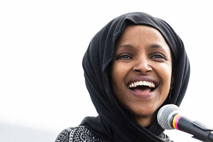 Smiling woman in hijab speaking into a microphone.