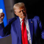 Man in blue suit with red tie speaking