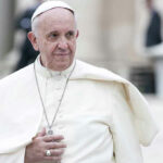 Man in white religious robe and cap outdoors.