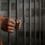 Murder Leader FREED — 17 Life Sentences Now Meaningless? Hands gripping prison cell bars tightly.