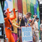 People celebrating at Pride parade, holding signs and flags.