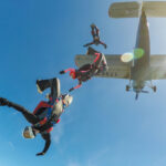 Skydivers freefalling below a small aircraft blue sky
