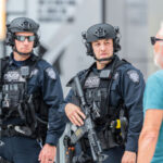 Two armed police officers engaging with a man outside.