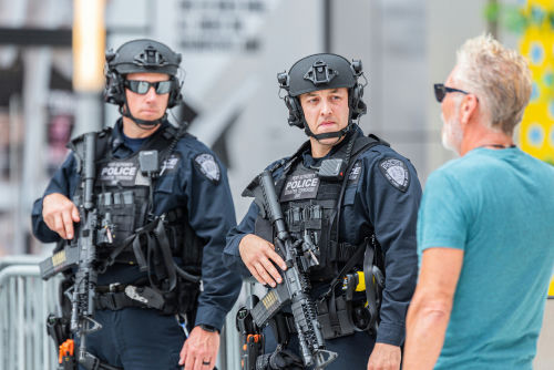 Two armed police officers engaging with a man outside.