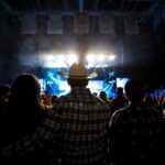 Audience at a concert with a person in a cowboy hat in the foreground