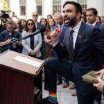 A speaker at a podium passionately addressing a crowd, wearing rainbow socks