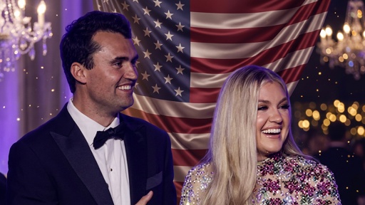 A smiling couple in formal attire standing in front of an American flag backdrop
