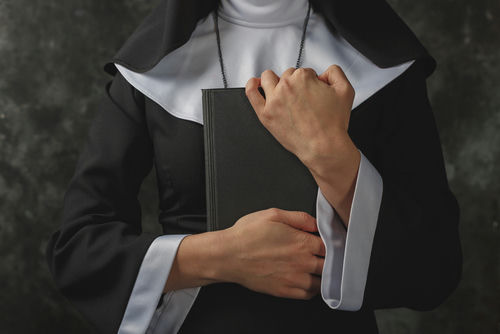 A nun in traditional attire holding a book close to her chest