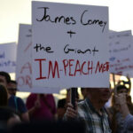Raúl Castro INDICTED – Justice Finally Arrives? Protestors with signs, central sign references James Comey.