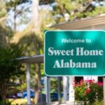 Trump-Endorsed Secures Senate Nomination Green roadside sign reading Welcome to Sweet Home Alabama near a building and trees