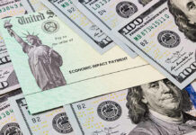 Economic Impact Payment check surrounded by hundred-dollar bills.