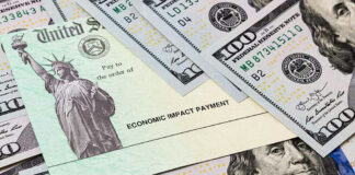 Economic Impact Payment check surrounded by hundred-dollar bills.