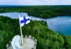 Nuclear Weapons Now Legal In Finland? Finnish flag flying on a stone tower above a forest and lake