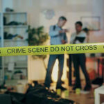 Crime scene tape in front of investigators and forensic unit.