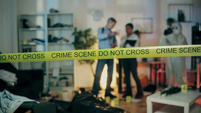 2386626691-1 Crime scene tape in front of investigators and forensic unit.