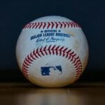 Baseball with red stitching on a wooden surface
