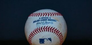 Baseball with red stitching on a wooden surface