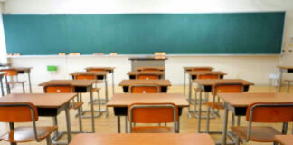 Empty classroom with wooden desks and chalkboard.