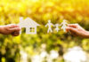 Hands holding paper cutouts of house and family.