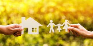 Hands holding paper cutouts of house and family.