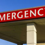 Red and white Emergency sign outside building.