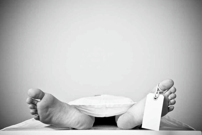 Bare feet with toe tag on body covered by sheet.