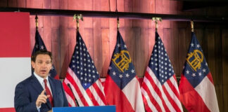 Man speaking at Florida Blueprint event with American flags.