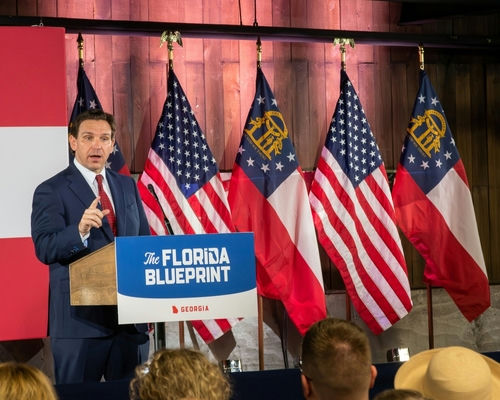 Man speaking at Florida Blueprint event with American flags.