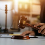 Judge's hand striking a wooden gavel on a sound block