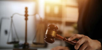 Judge's hand striking a wooden gavel on a sound block