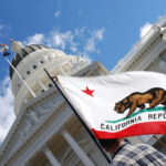 California Voters Face Wealth Tax Showdown California state flag waving near a white domed capitol building