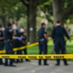 Unthinkable Crossbow ATTACK — VICTIM Blindsided! Police officers behind yellow crime scene tape in park.