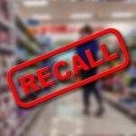 A blurred grocery store aisle with a prominent RECALL sign in red