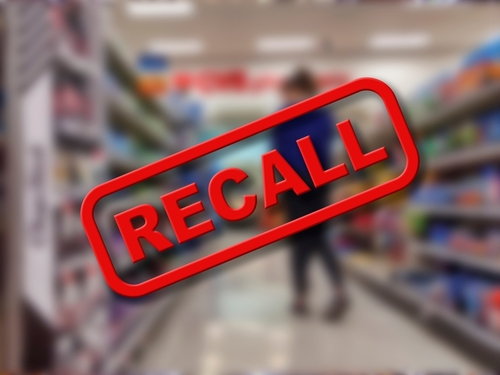 A blurred grocery store aisle with a prominent RECALL sign in red