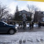 Law enforcement officers in tactical gear at a crime scene surrounded by police tape