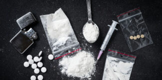 Drug paraphernalia including syringes, pills, and powder.
