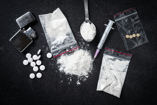 shutterstock_413804086 Drug paraphernalia including syringes, pills, and powder.