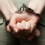 Person in handcuffs with hands behind back.