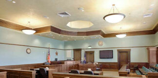 Empty courtroom with wooden benches and desks.
