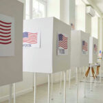 Voting booths with American flag signs.