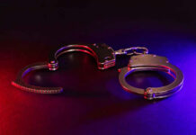 Five Noncitizens Charged With Illegal Voting Handcuffs illuminated by red and blue lights.
