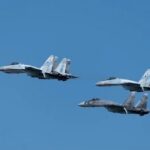 Silhouettes of three fighter jets flying above clouds at sunrise