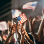 American flag held above a cheering crowd