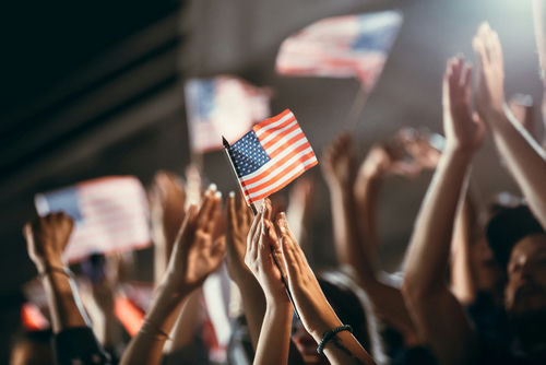 American flag held above a cheering crowd