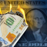 Burning US hundred-dollar bill with flames at the corner