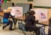 Election Fraud Admitted — Justice Shrugs Voters seated at booths filling out ballots in a polling place