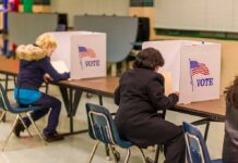 Election Fraud Admitted — Justice Shrugs Voters seated at booths filling out ballots in a polling place