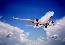 Commercial airplane flying with landing gear extended against a blue sky
