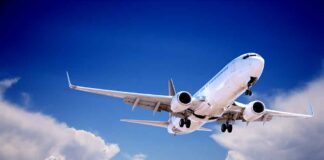 Commercial airplane flying with landing gear extended against a blue sky