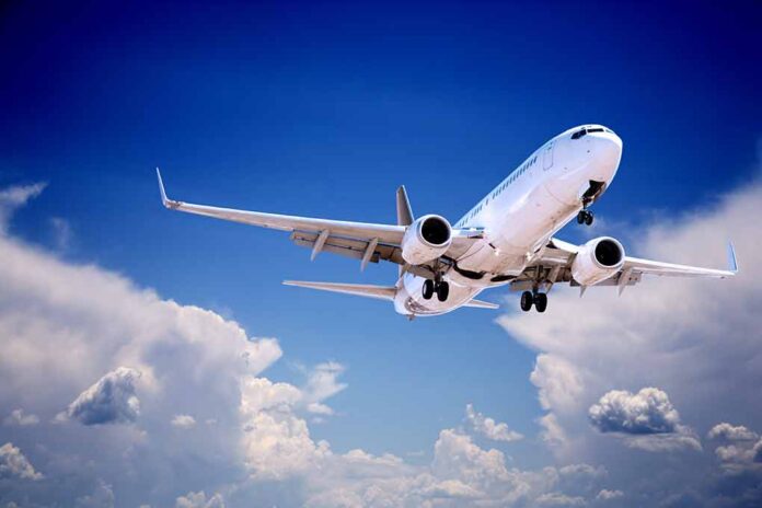 shutterstock_105724190 Commercial airplane flying with landing gear extended against a blue sky